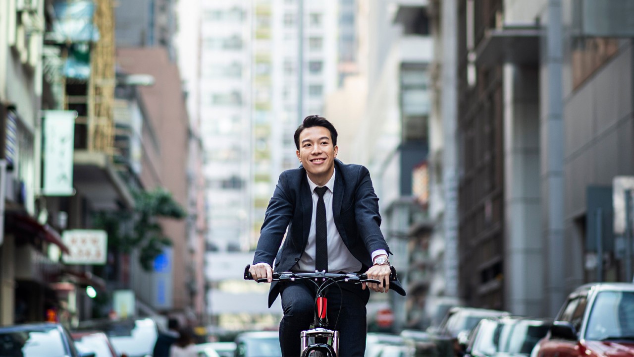 一位男士在鬧市中騎單車；圖片使用於滙豐One能投資講堂頁面。 